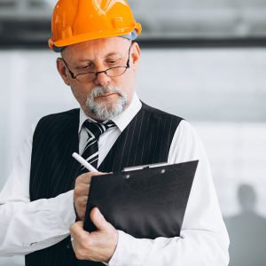 Coordinatore per la sicurezza nei cantieri con casco protettivo compila documenti tecnici